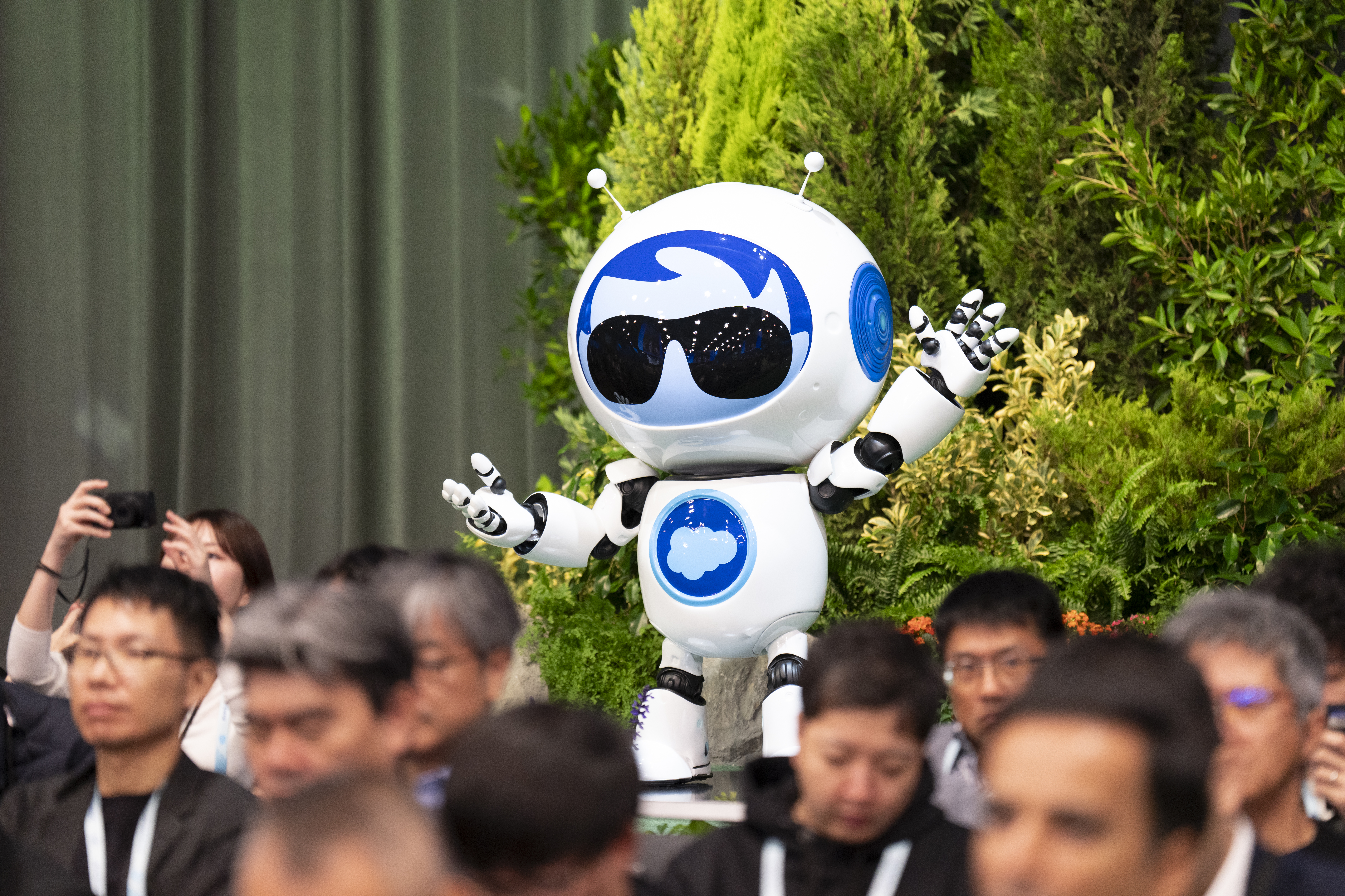 Salesforce robot mascot at Dreamforce 2025. He's wearing a white suit with a cloud on his chest.