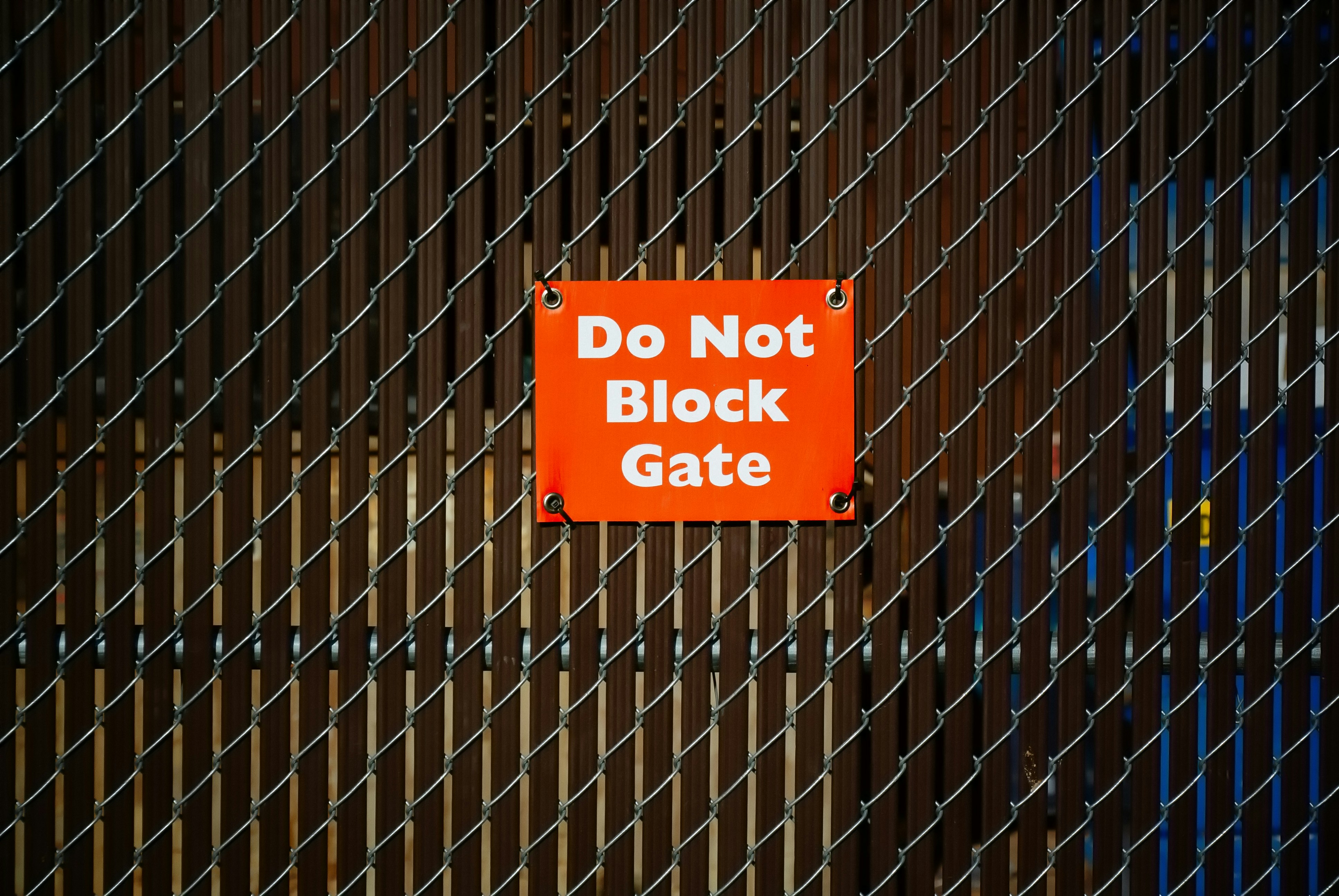 Gate with red sign with white block letters that says 'Do not block the gate.'