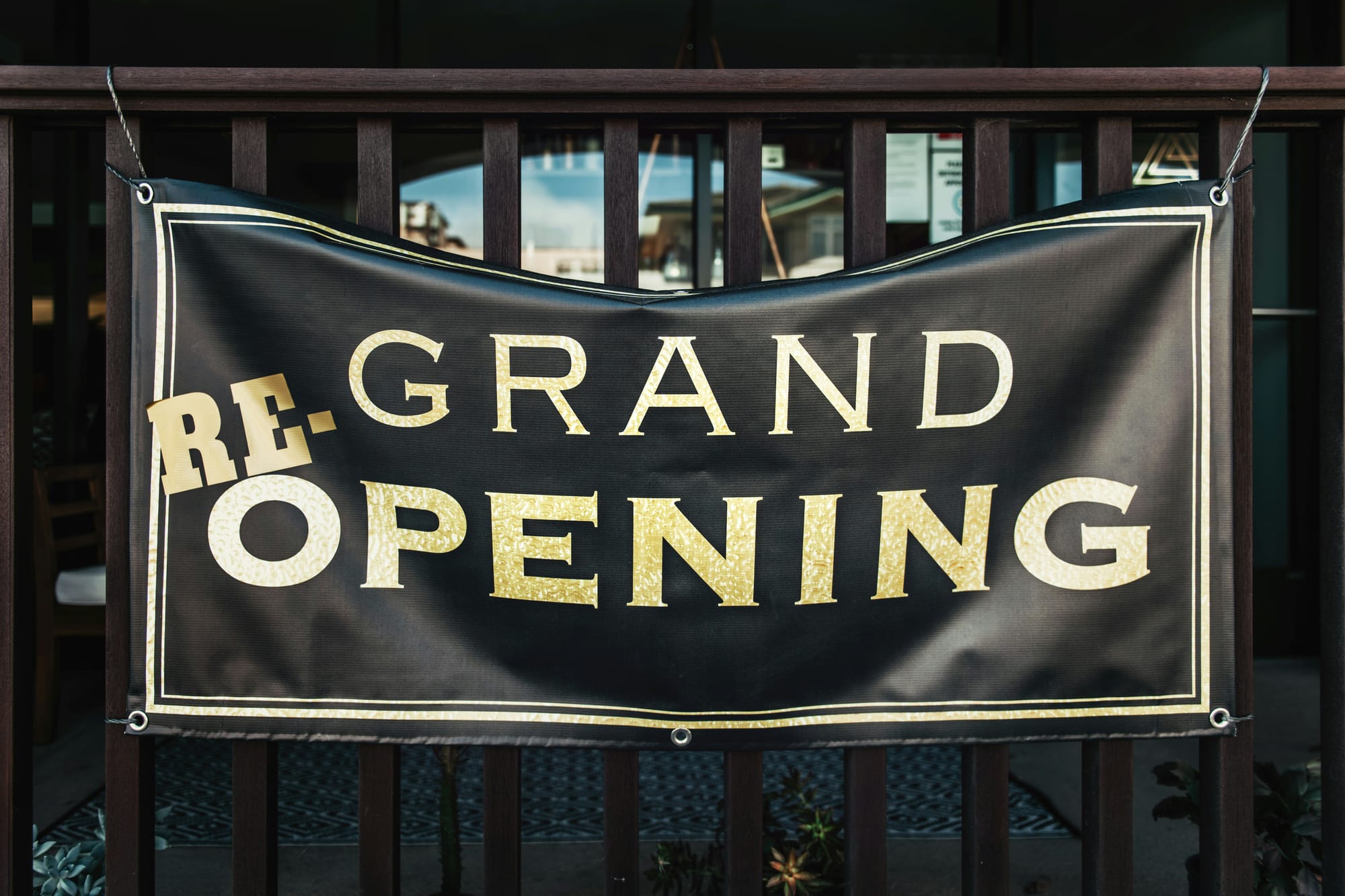 Banner reading “Re-Grand Opening” hanging on a wooden railing